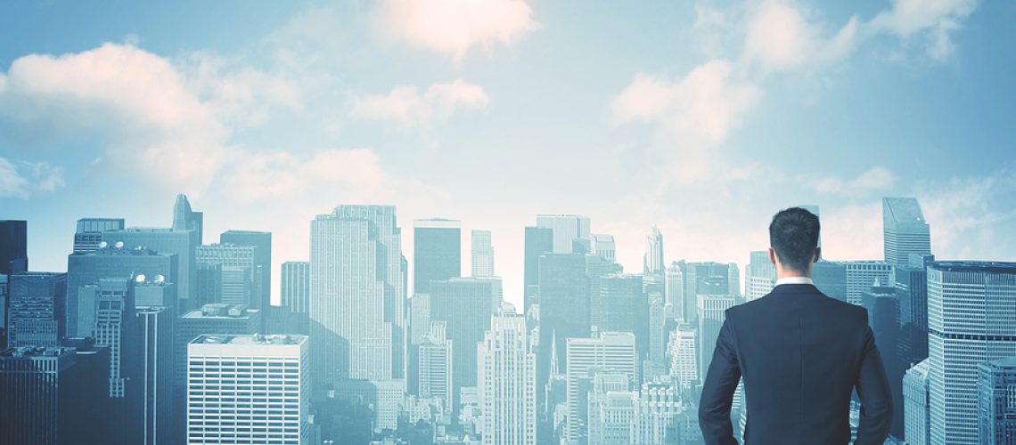 Businessman standing on a roof and looking at future city